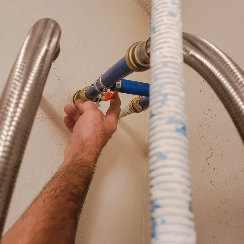 new-plumbing-over-hot-water-heater-and-mans-hand-2023-11-27-05-22-22-utc